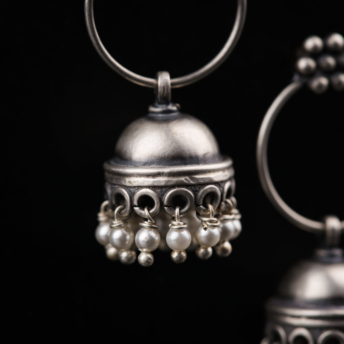 a metal bell with pearls hanging from it