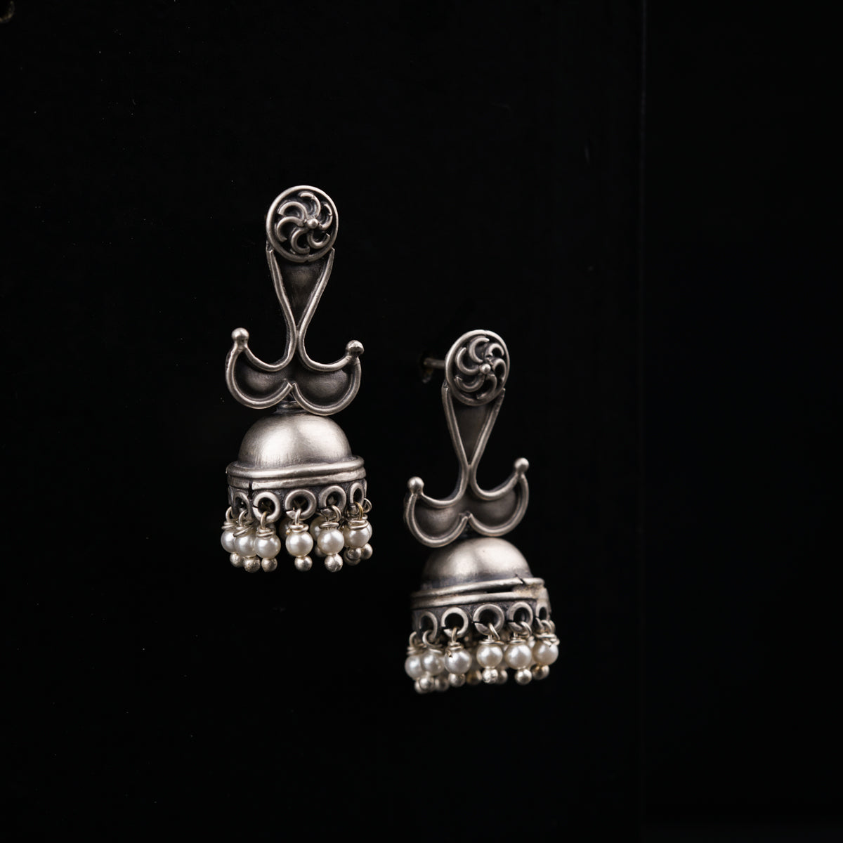 a pair of silver bells with pearls on them