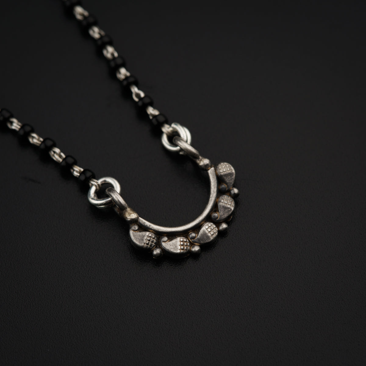 a black and silver necklace on a black surface