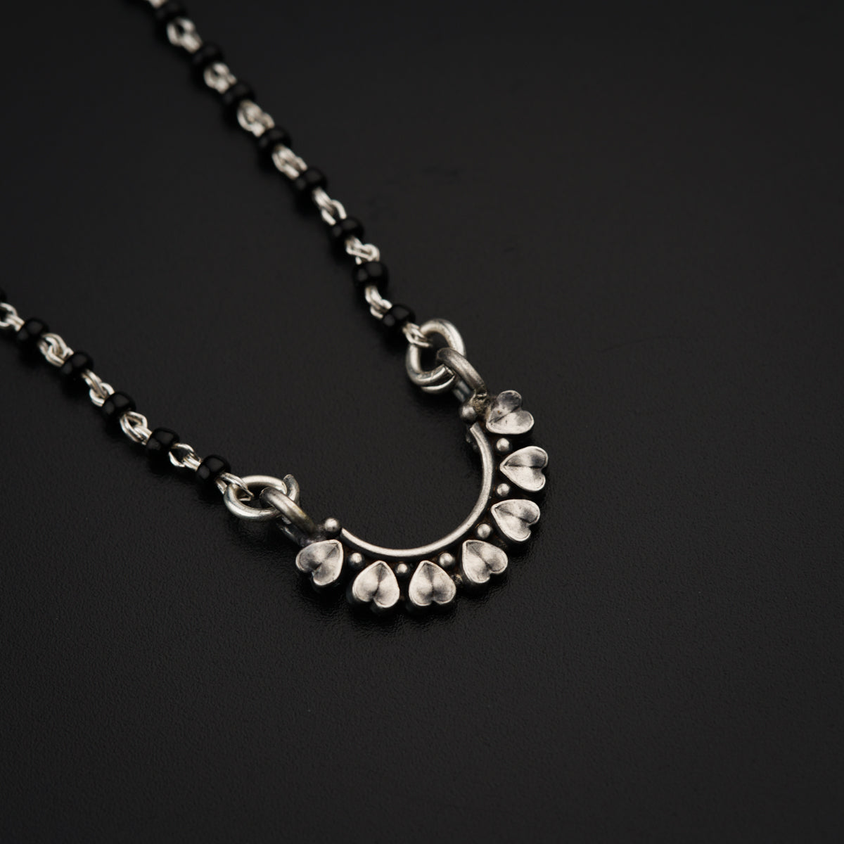 a black and silver necklace on a black surface