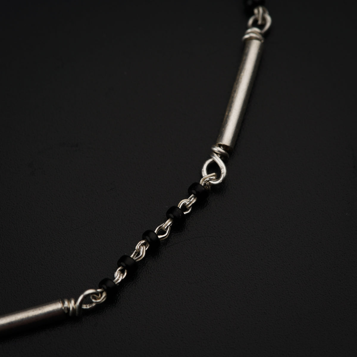 a silver chain with a black bead on it