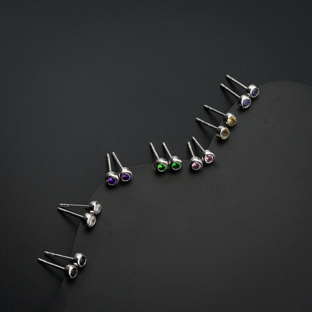 a set of five pairs of earrings on a black surface