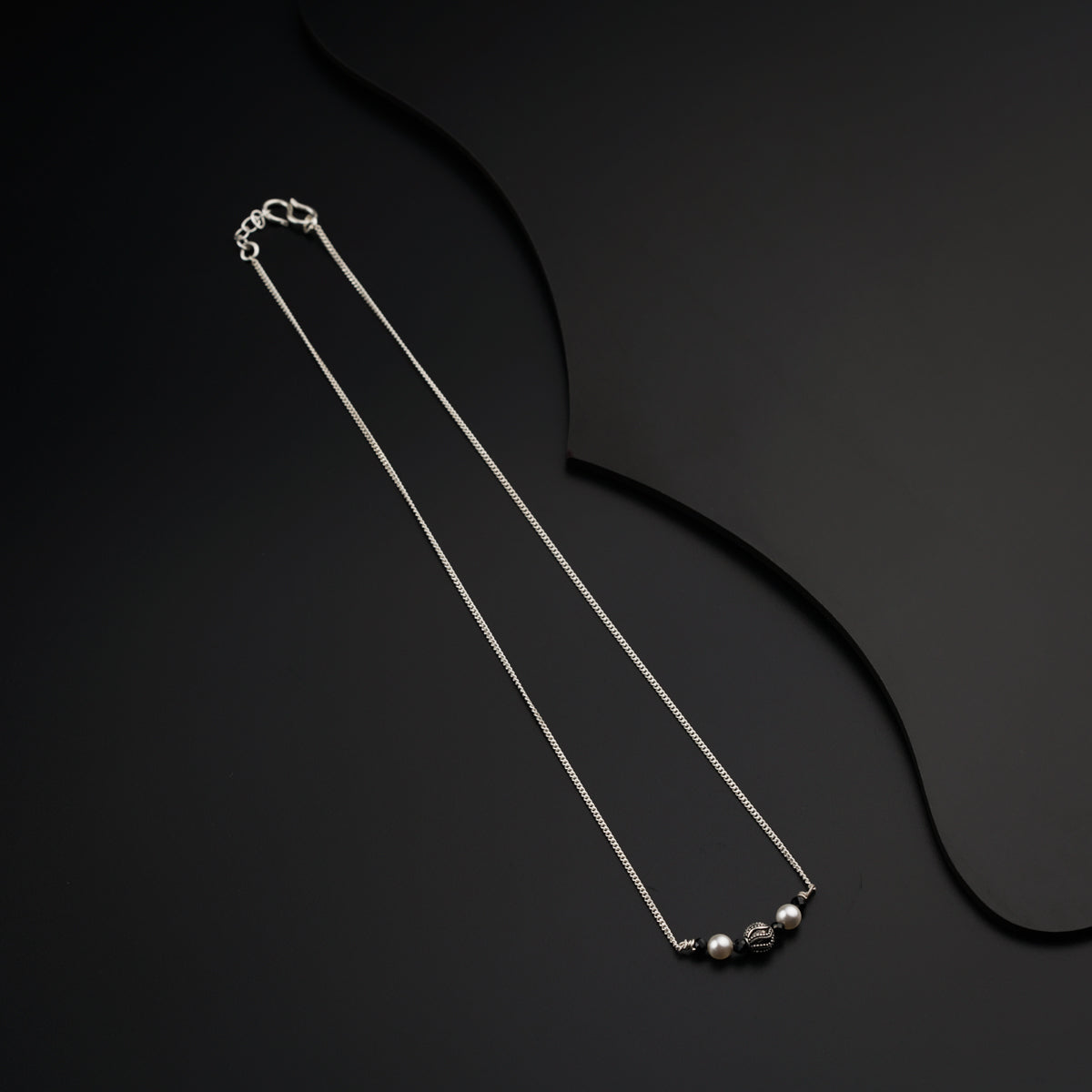 a pair of silver necklaces on a black background
