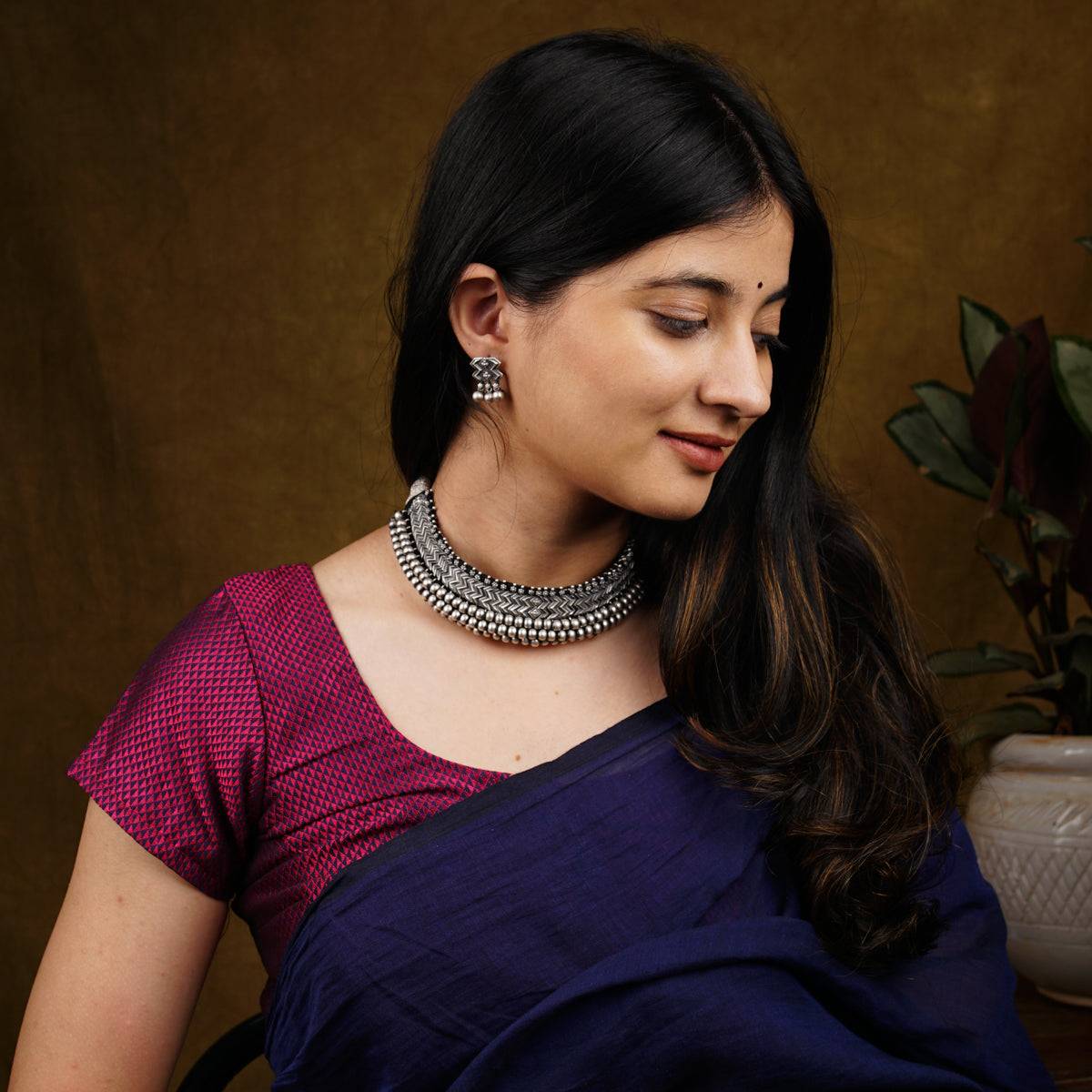 a woman wearing a necklace and a purple saree