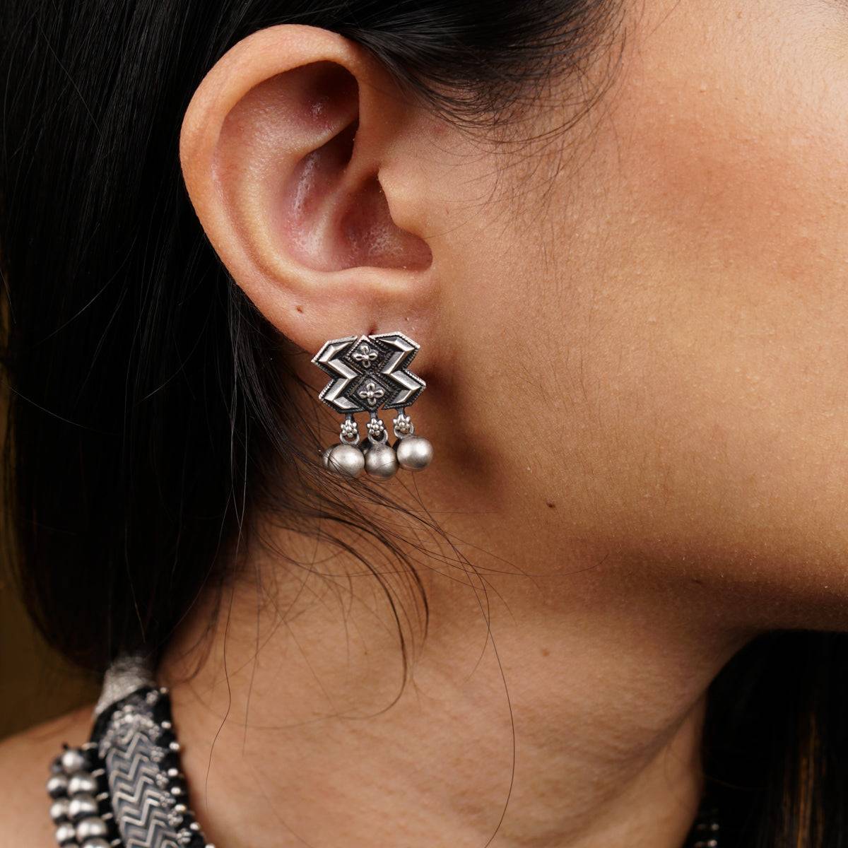 a close up of a person wearing a necklace and earrings