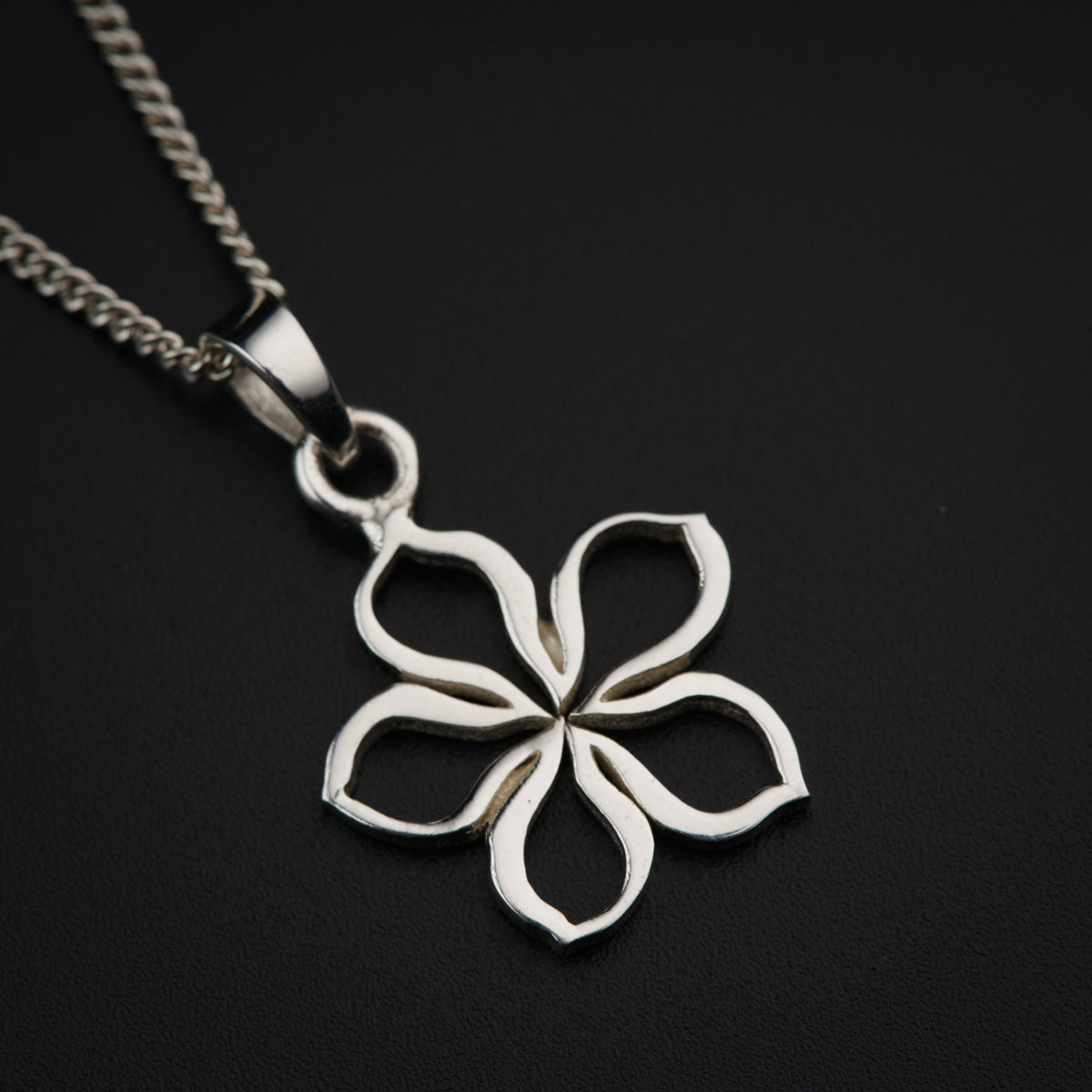 a silver pendant with a flower on a chain