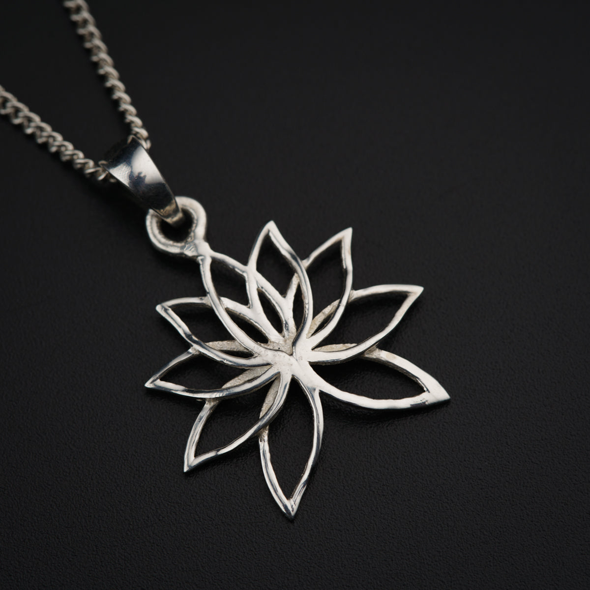 a silver pendant with a flower on a chain