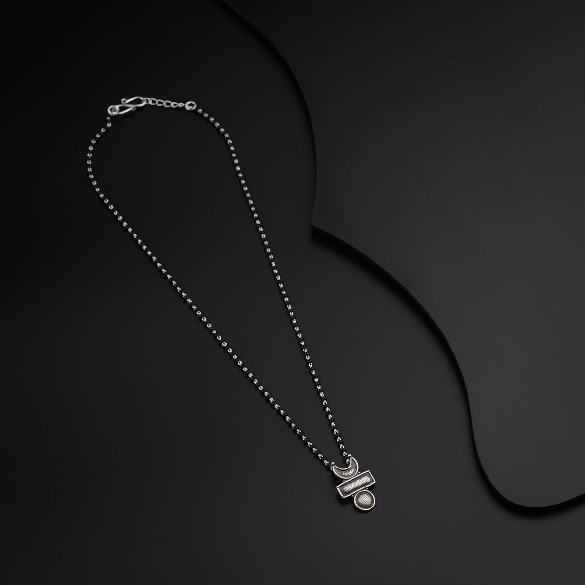 a black necklace with a silver chain on a black background