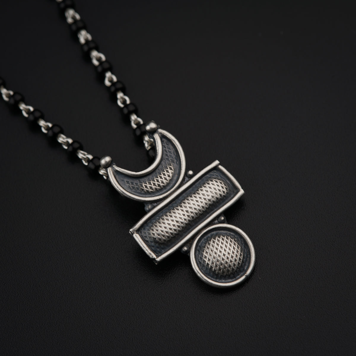 a black necklace with a metal object hanging from it's side