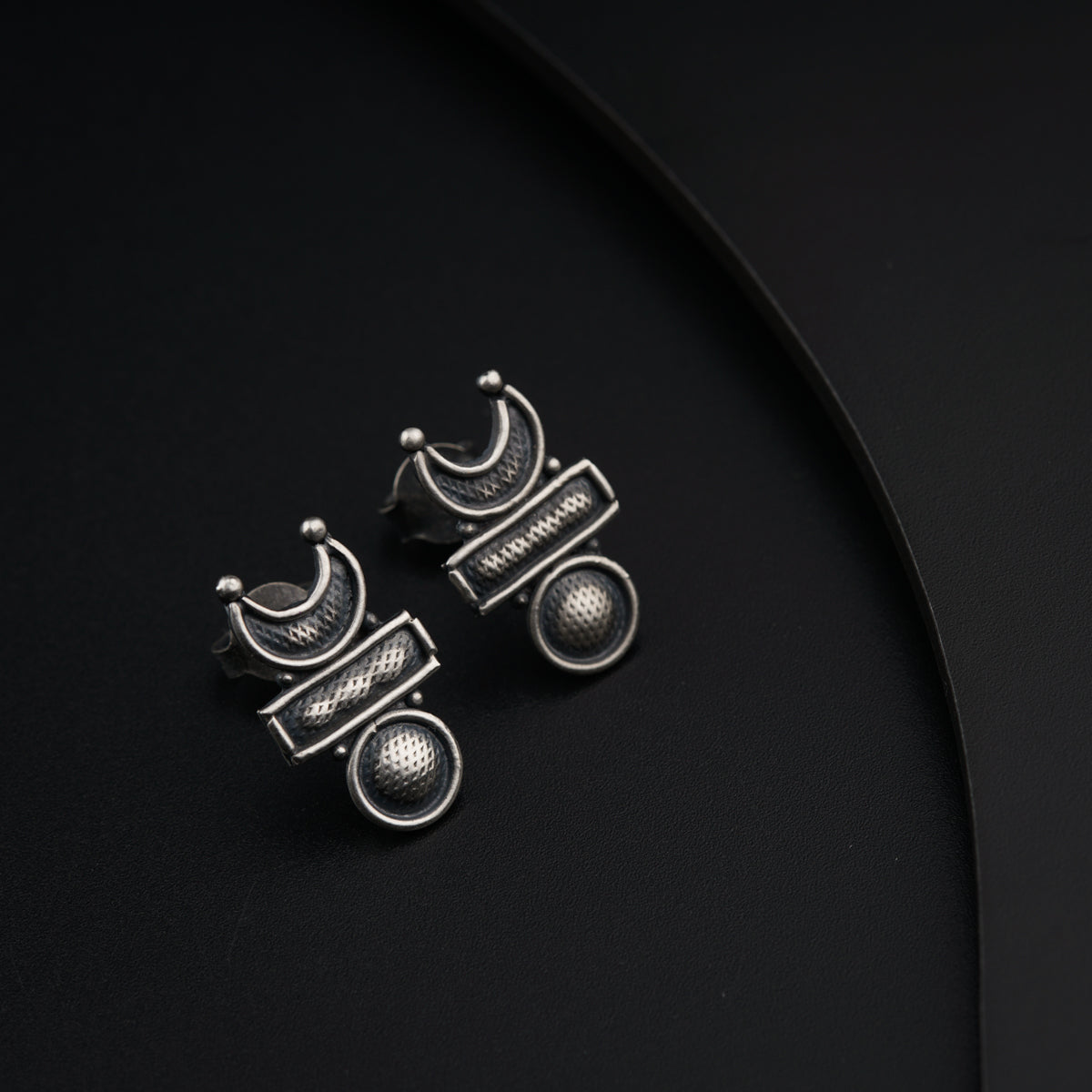 a pair of earrings sitting on top of a black surface