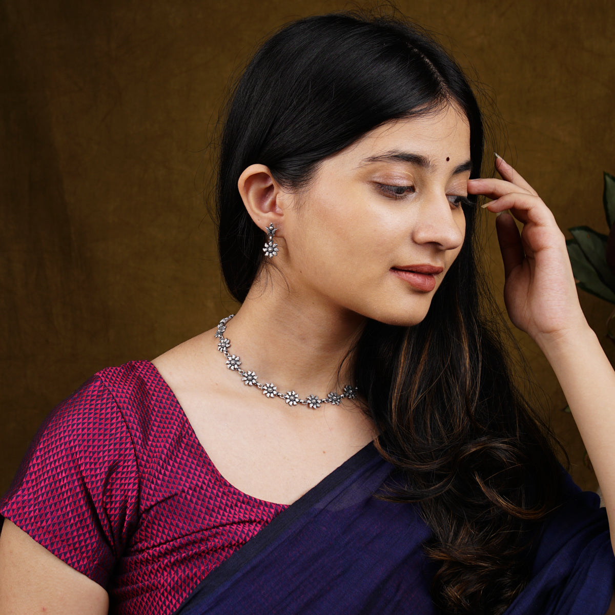 a woman wearing a necklace and a purple saree