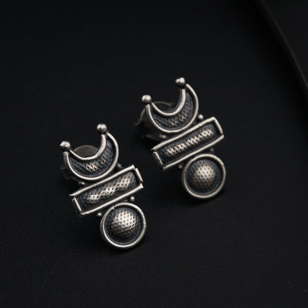 a pair of earrings sitting on top of a black surface