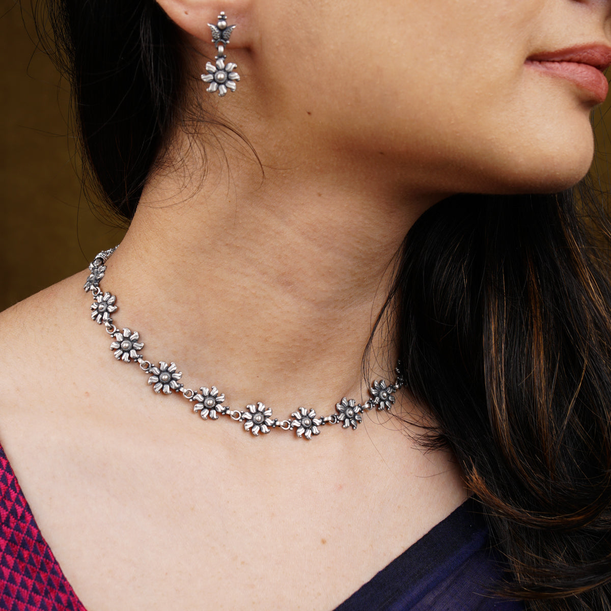 a close up of a woman wearing a necklace and earrings