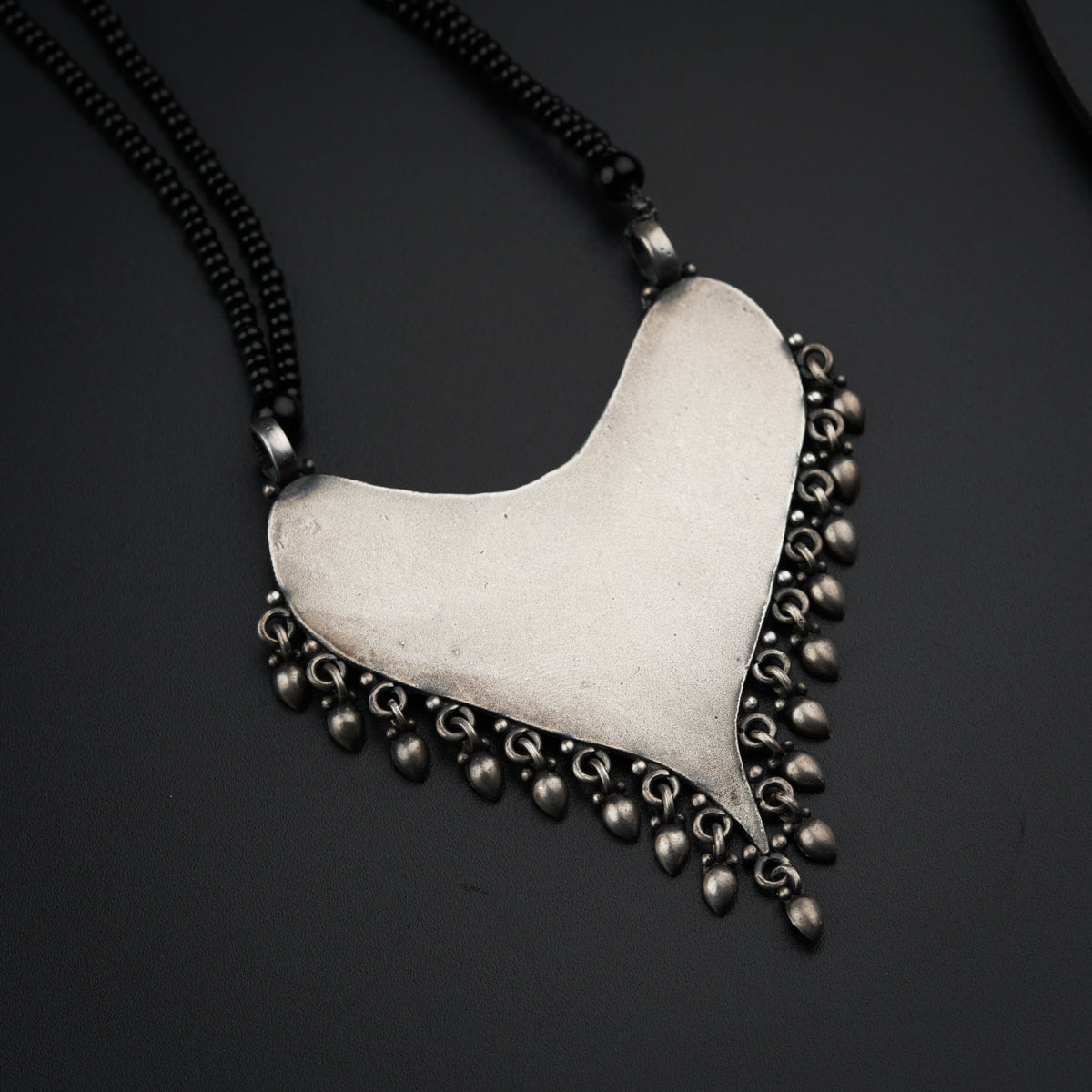 a white heart shaped pendant on a black background