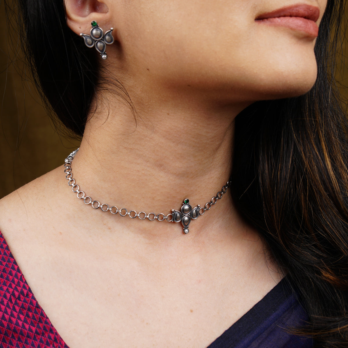 a close up of a woman wearing a necklace and earrings