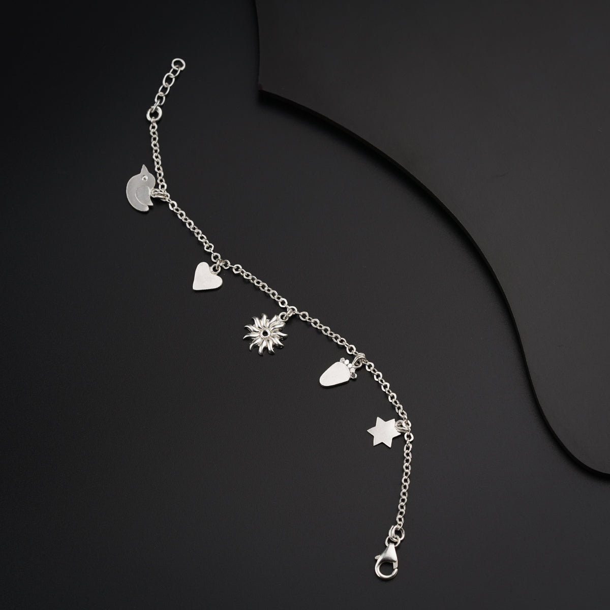 a silver bracelet with hearts and stars on a black background