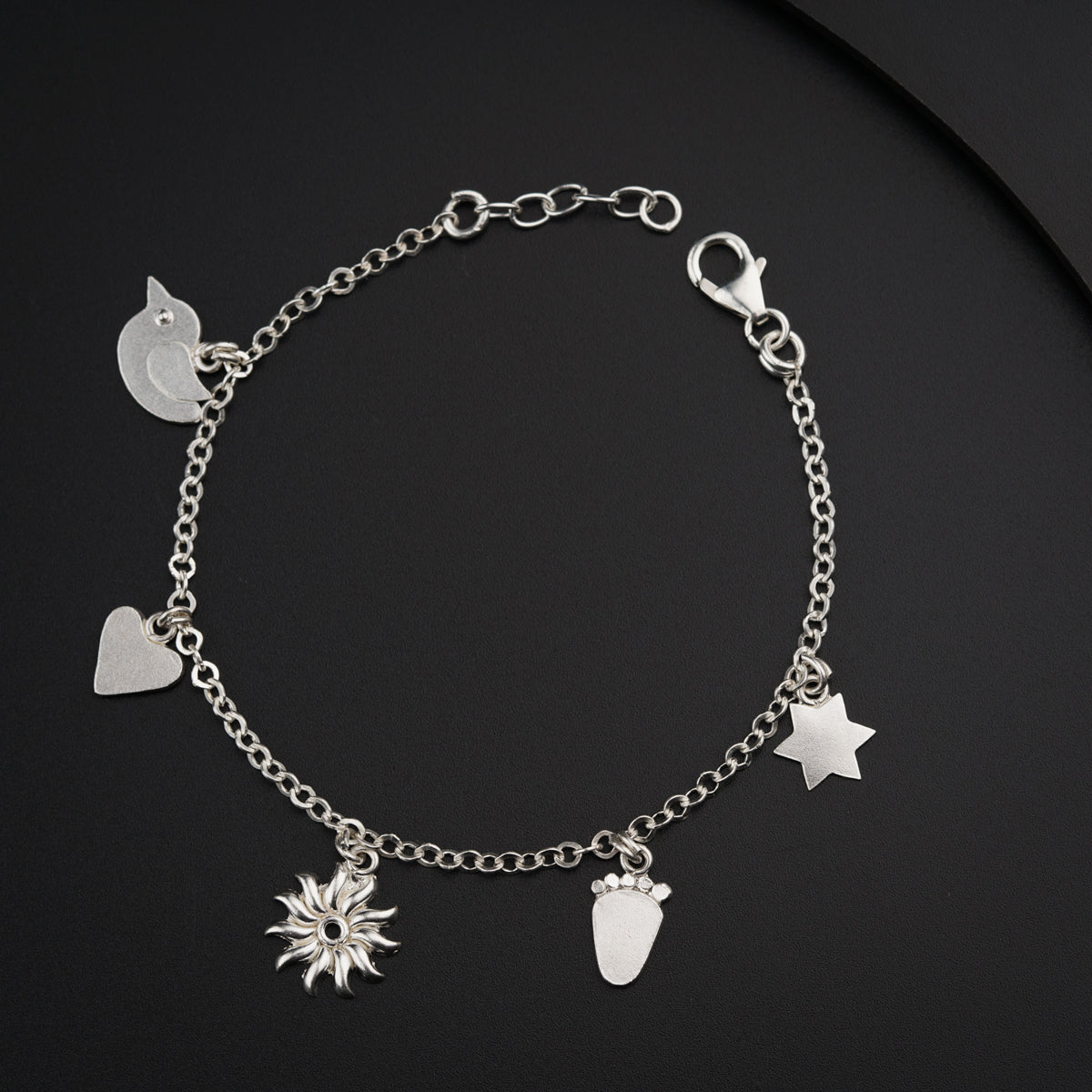 a silver bracelet with charms on a black surface