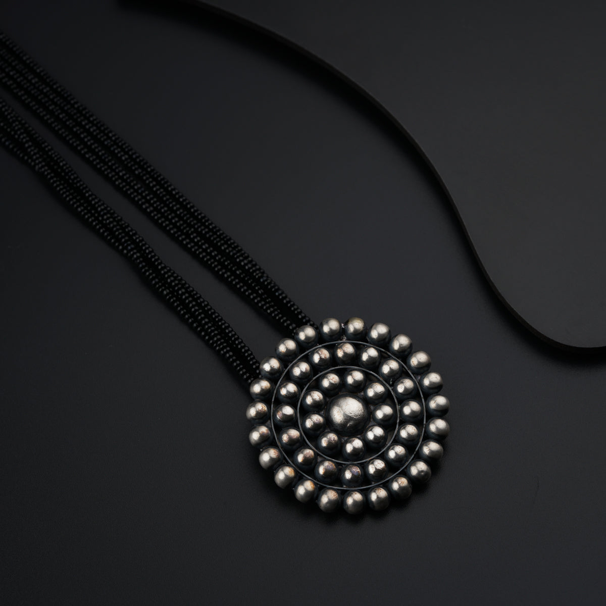 a black necklace with silver beads and a black cord