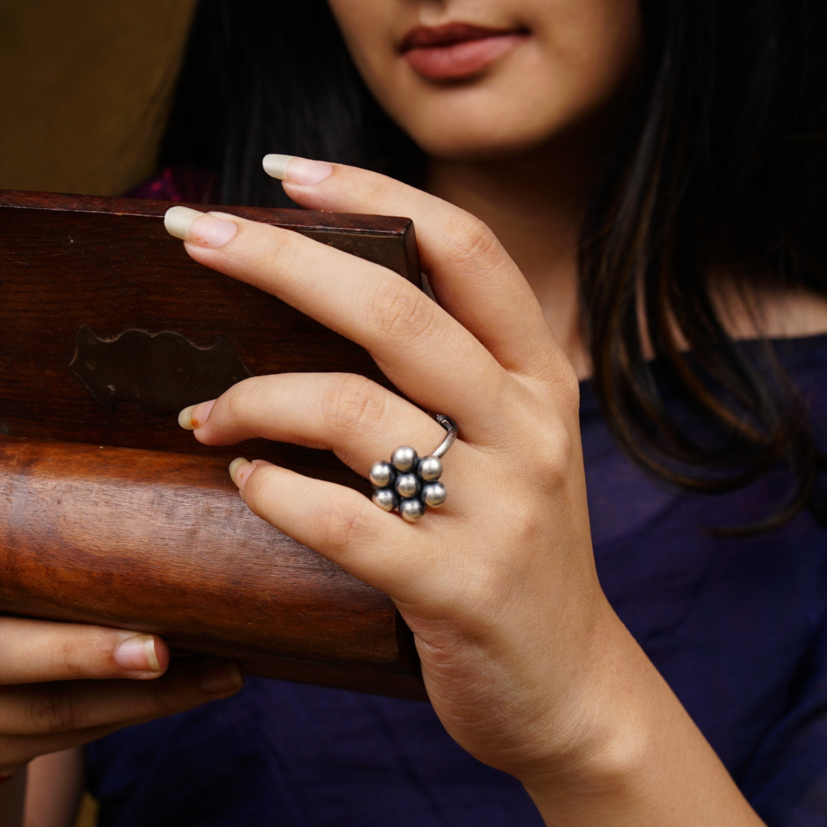 a woman holding a wooden case with a ring on it