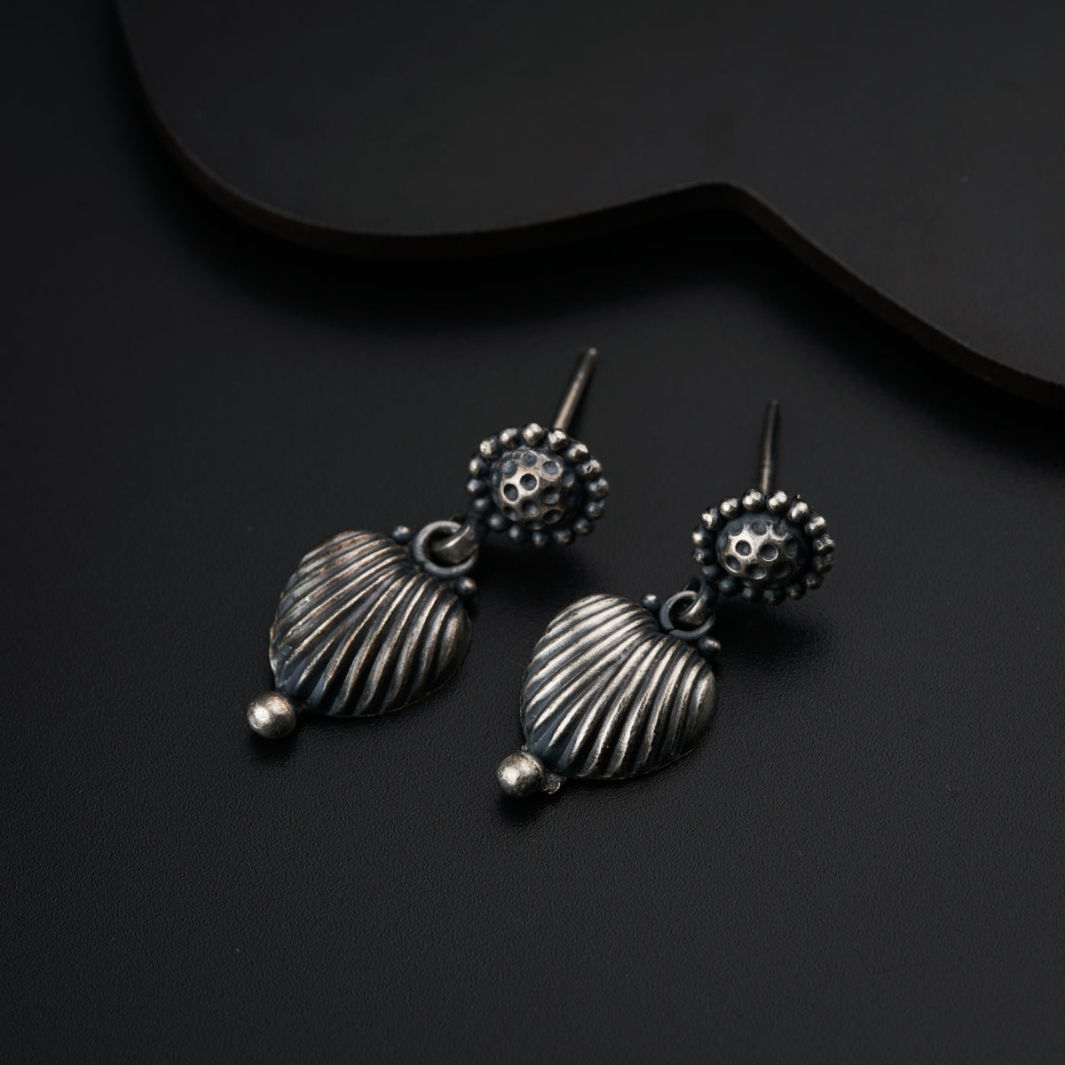 a pair of silver earrings sitting on top of a black surface