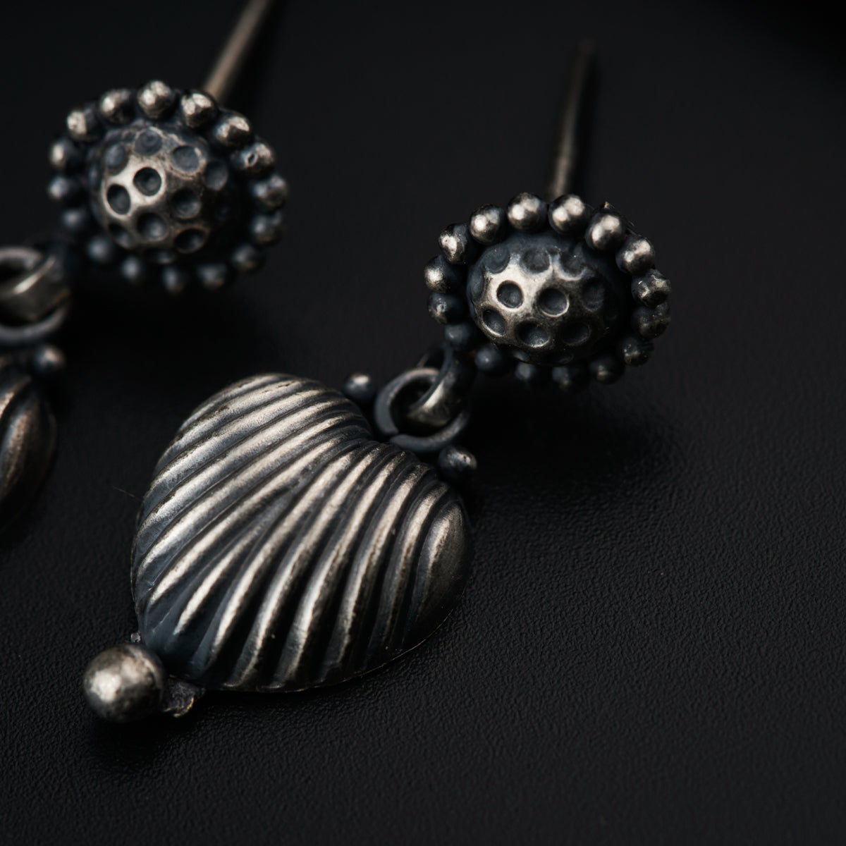 a close up of a pair of earrings on a black surface