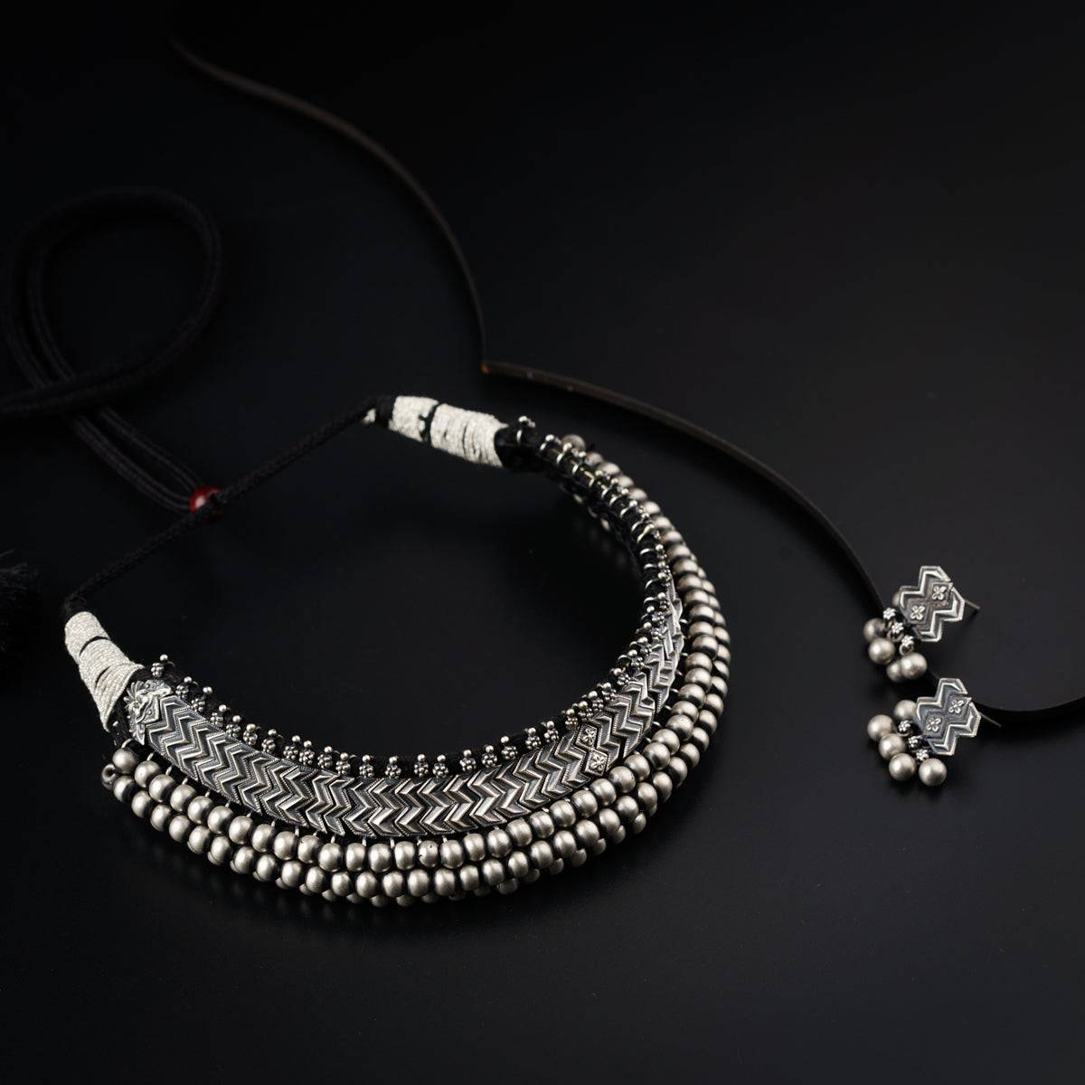 a black and white necklace and earring on a black surface