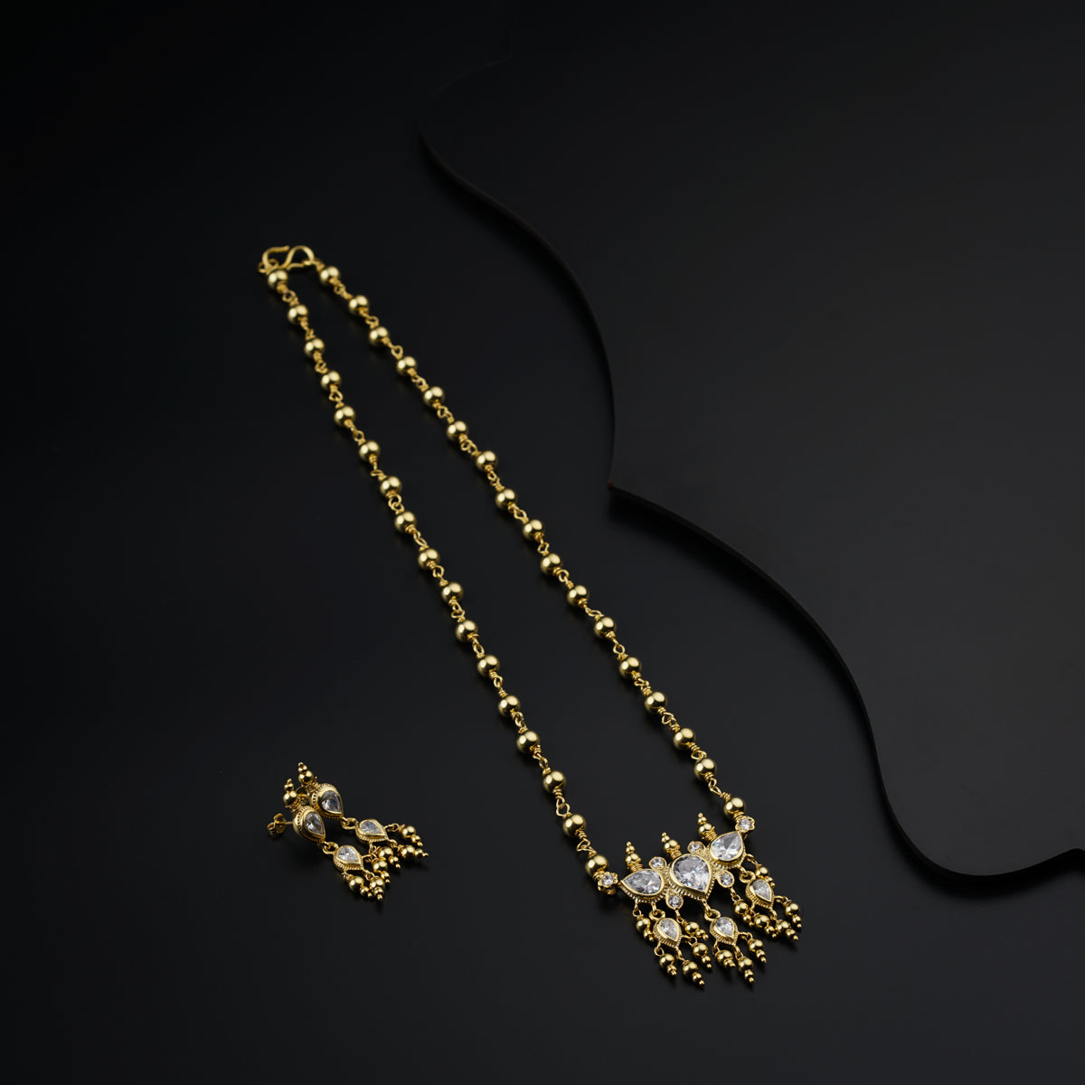 a pair of earrings and a necklace on a black surface