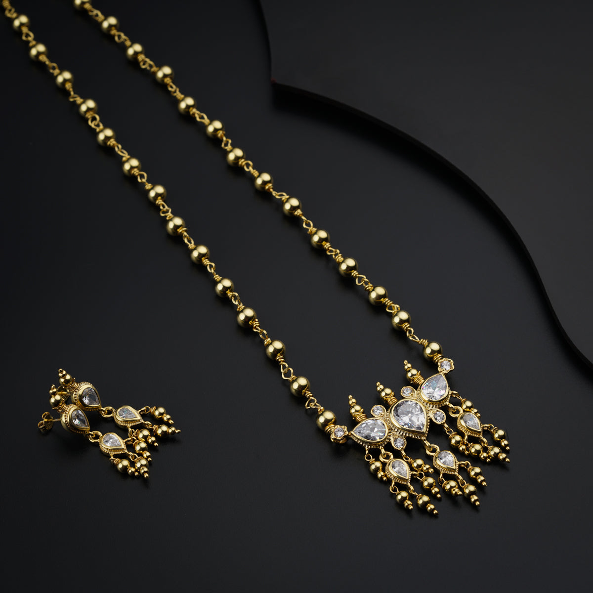 a gold necklace and earring set on a black surface