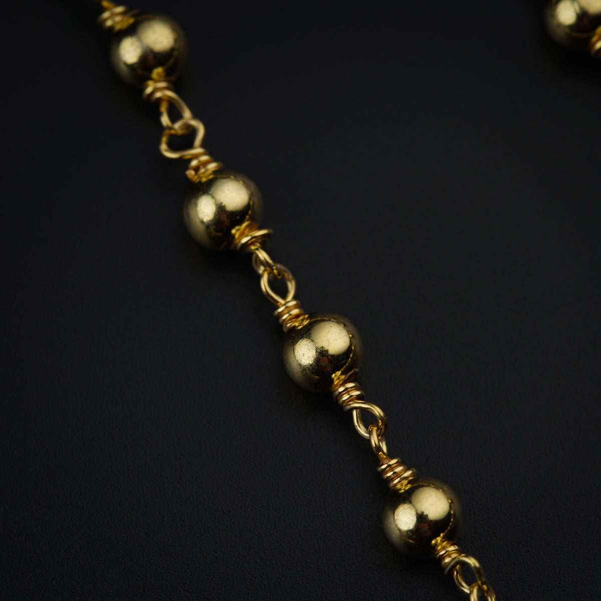 a close up of a gold chain on a black surface