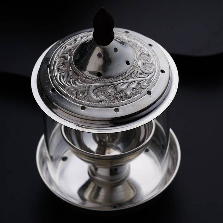 a silver plate with a lid on a black surface