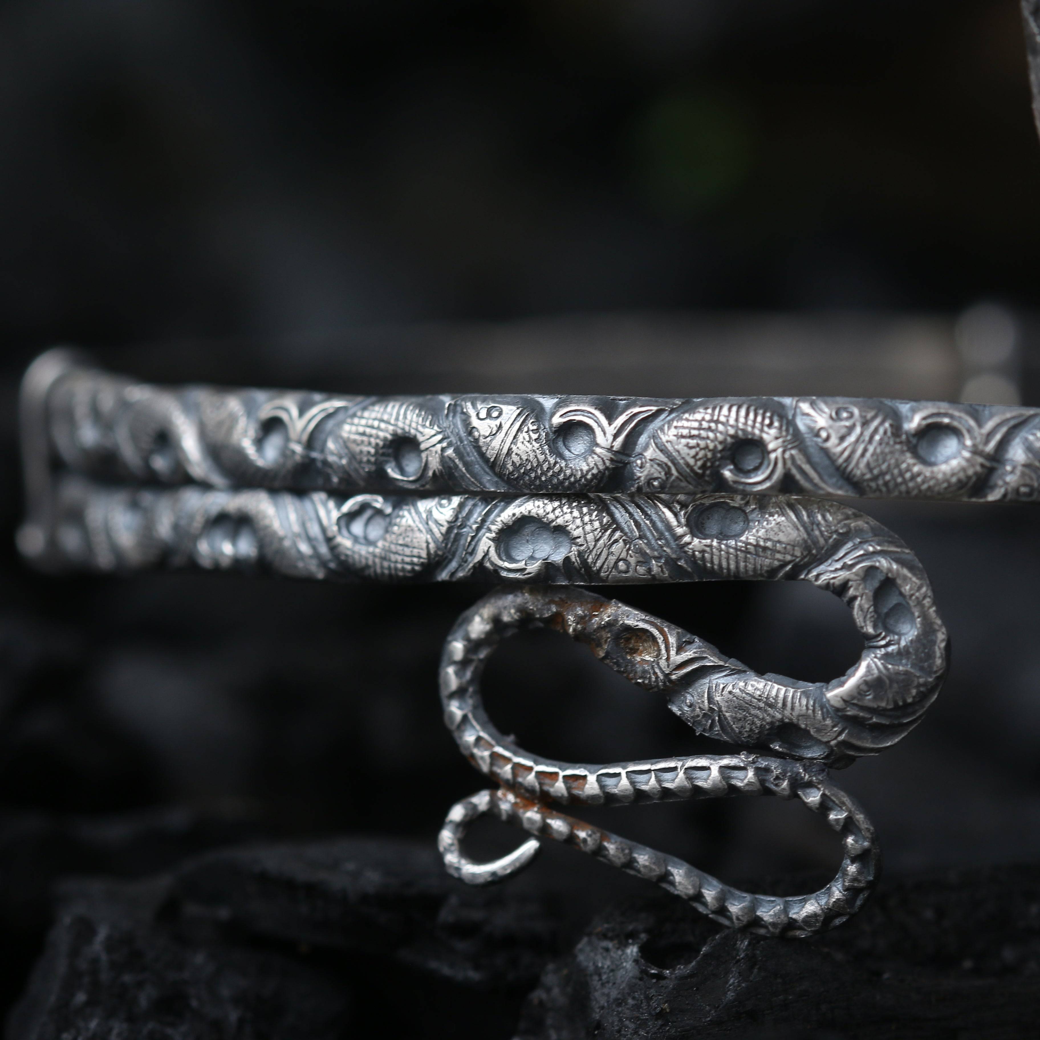 a close up of a silver bracelet on a rock