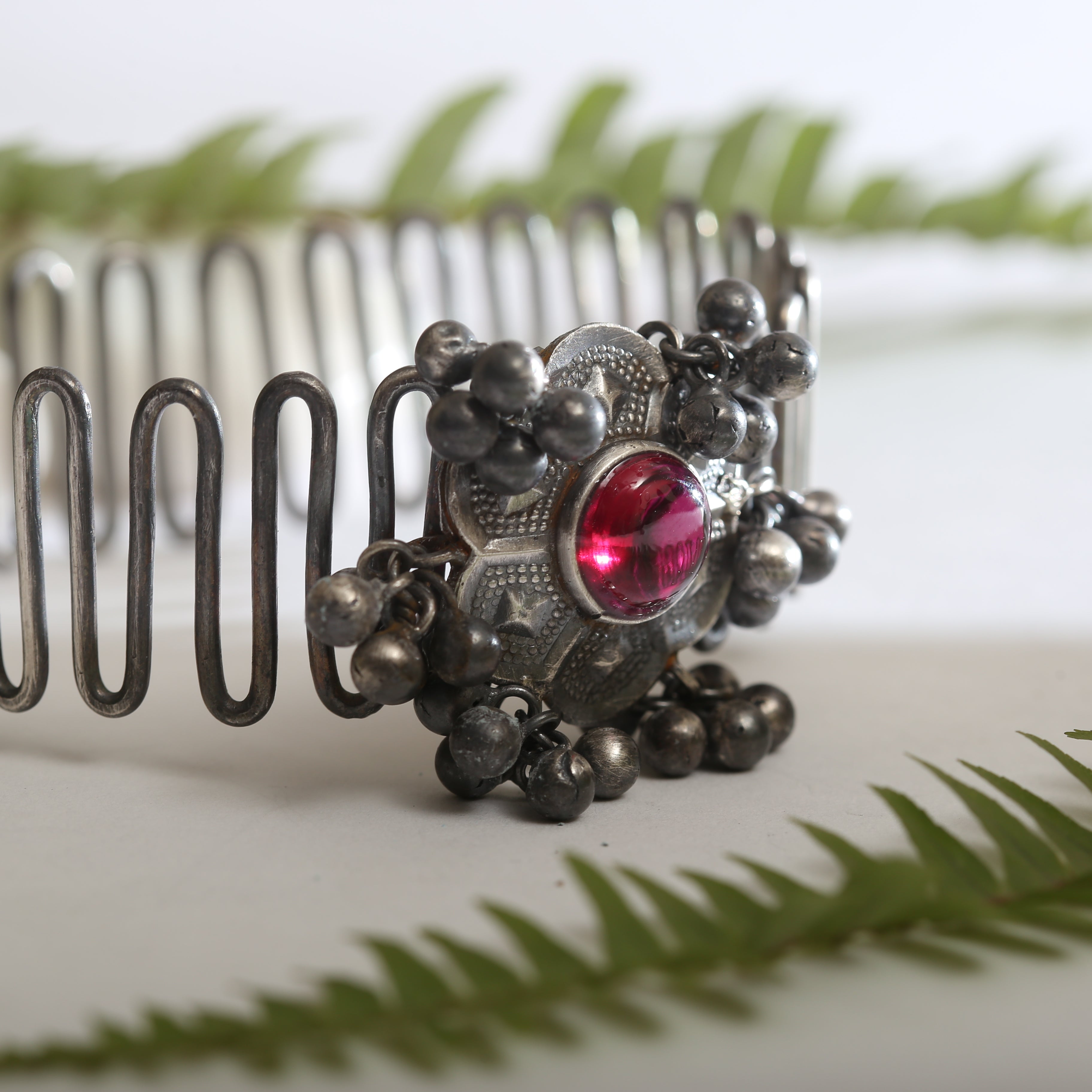 a close up of a hair comb with a red stone