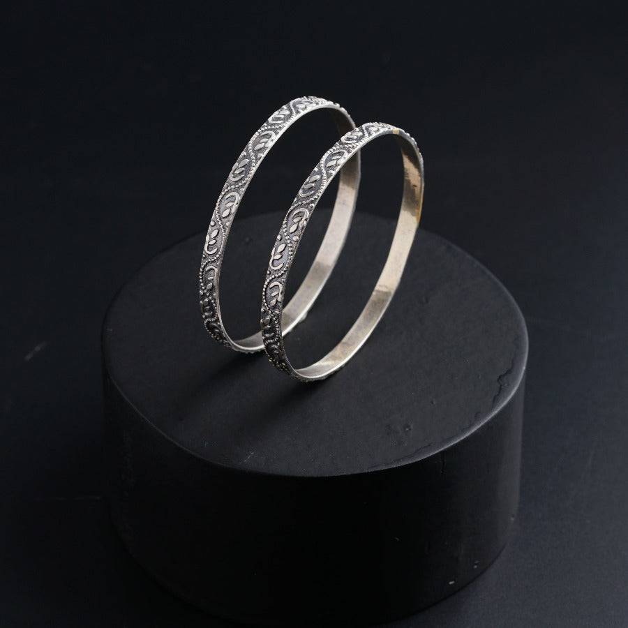 two silver rings sitting on top of a black surface