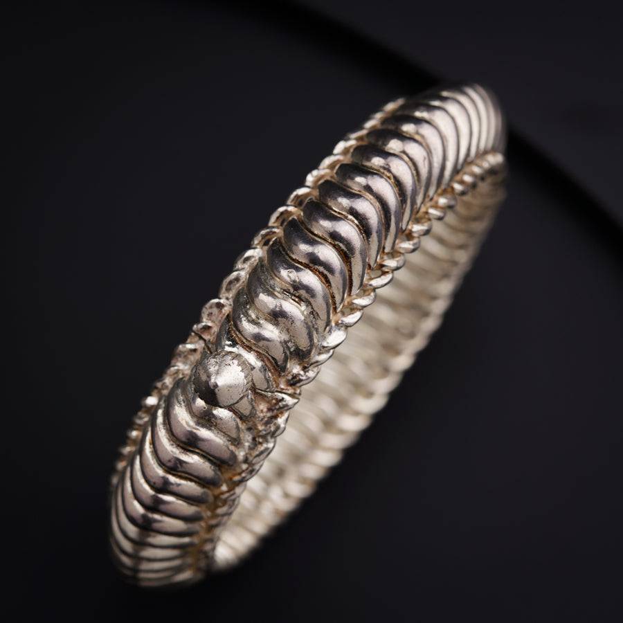 a close up of a silver bracelet on a black surface