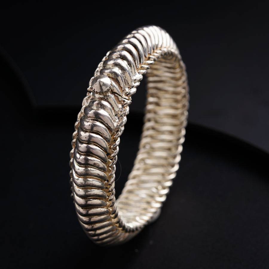 a close up of a silver bracelet on a black surface
