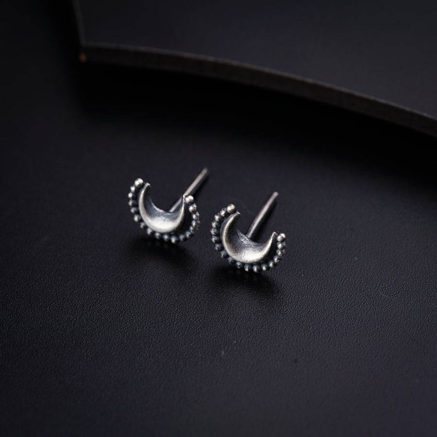 a pair of silver earrings sitting on top of a black surface