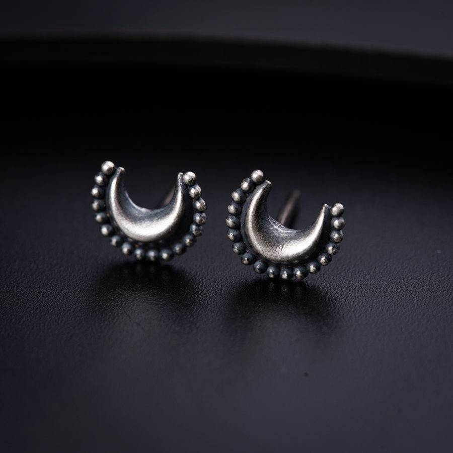 a pair of silver earrings on a black surface