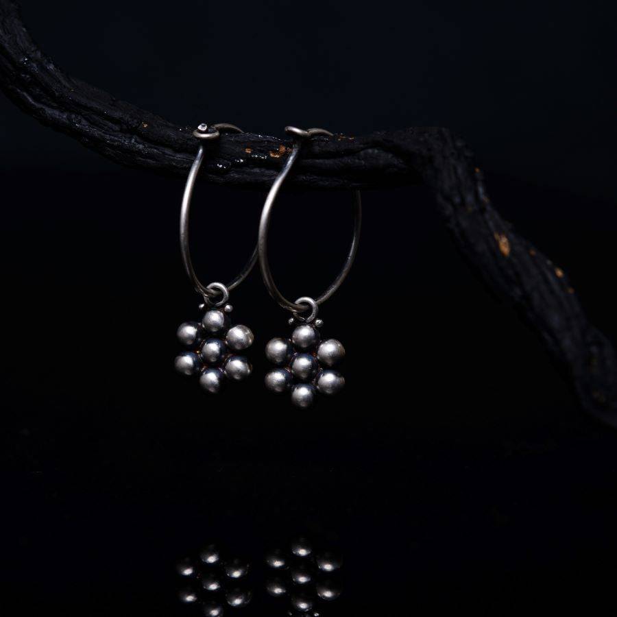 a pair of silver hoop earrings sitting on top of a black surface