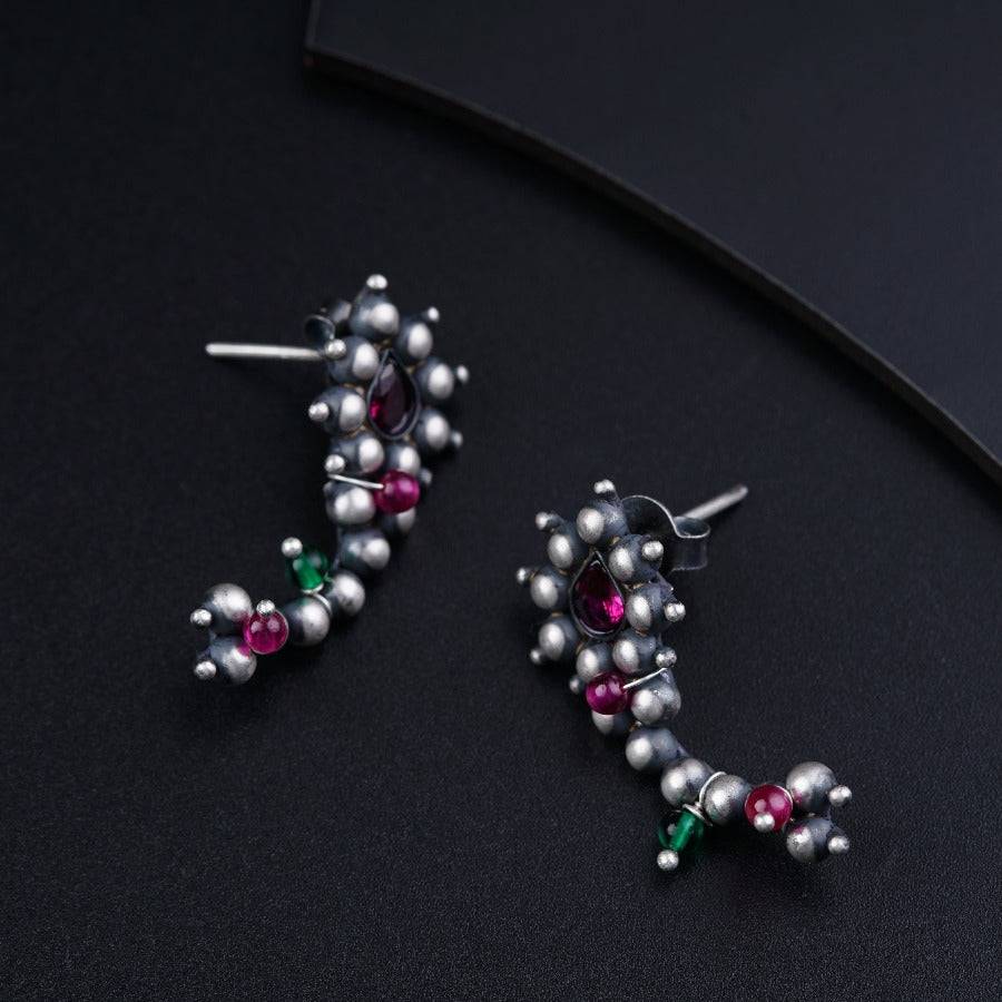 a pair of earrings with pearls and colored stones