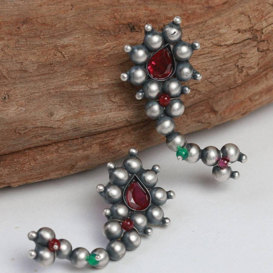 a close up of a pair of earrings on a piece of wood