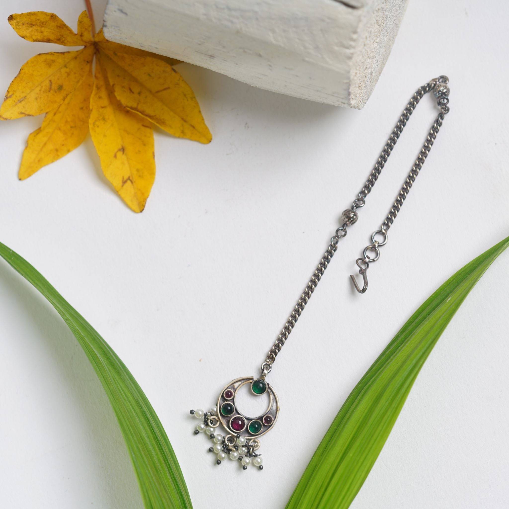 a necklace is laying on a table next to a flower