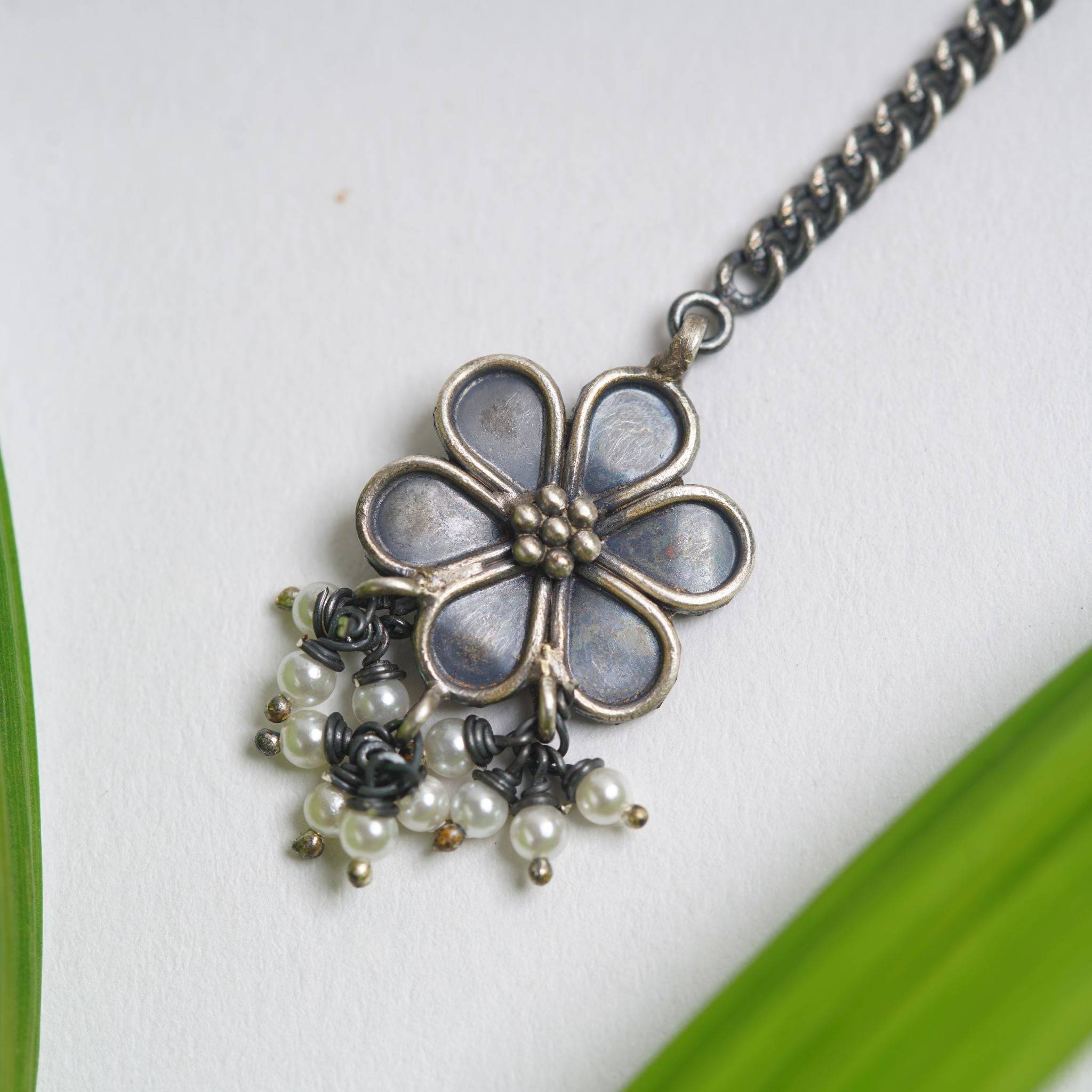 a necklace with a flower and pearls on a chain