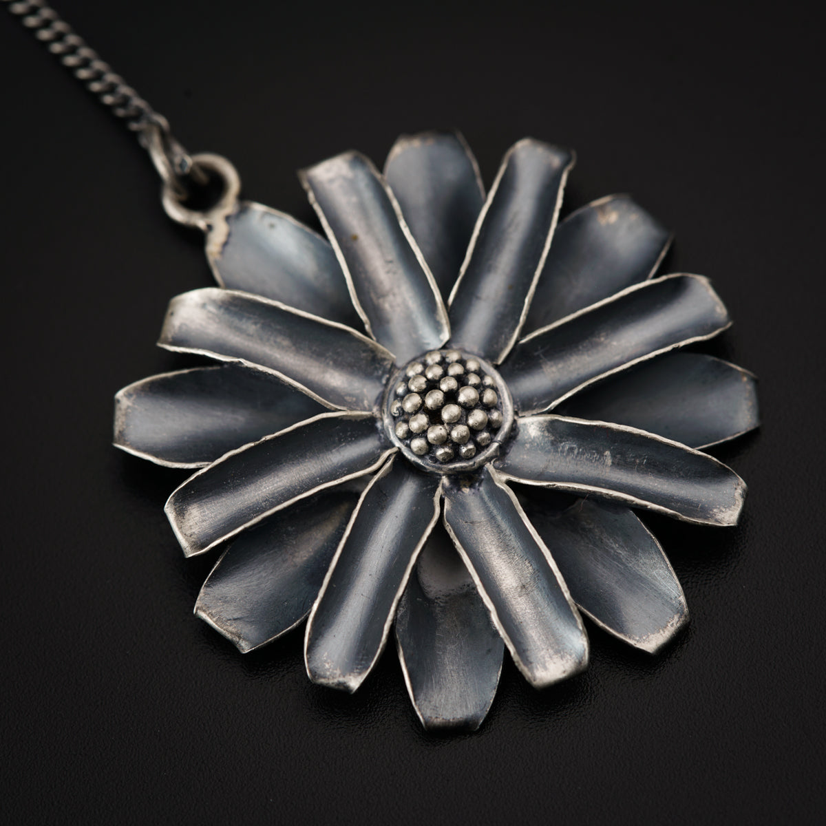 a silver necklace with a flower design on it