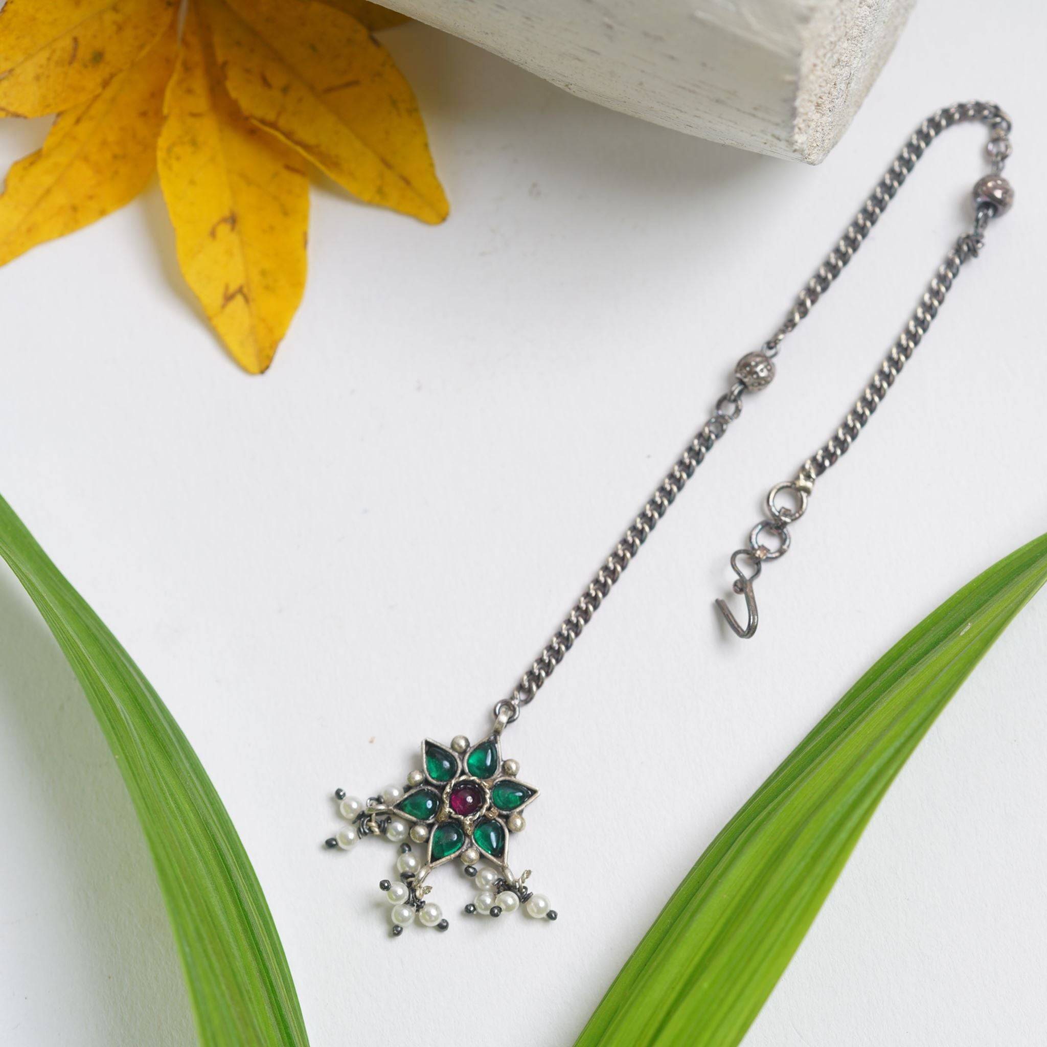 a necklace with a flower on it sitting next to a flower
