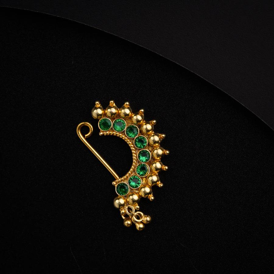 a green and gold brooch sitting on top of a black surface
