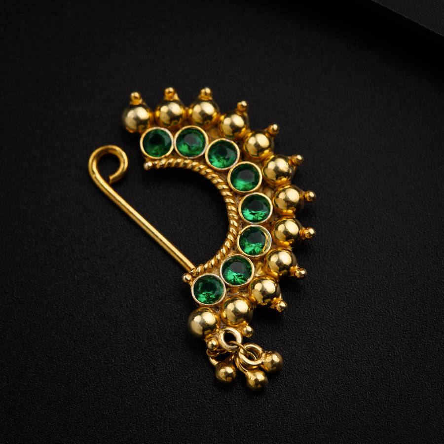a gold brooch with green stones and pearls