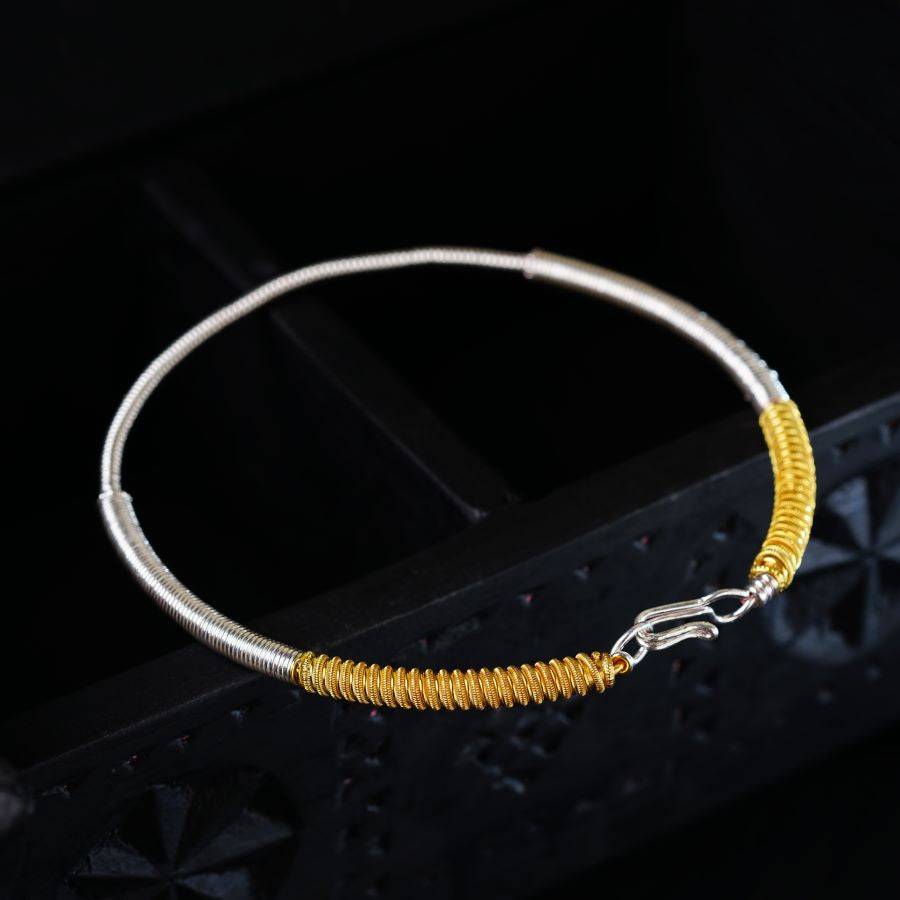 a yellow and silver bracelet on a black background