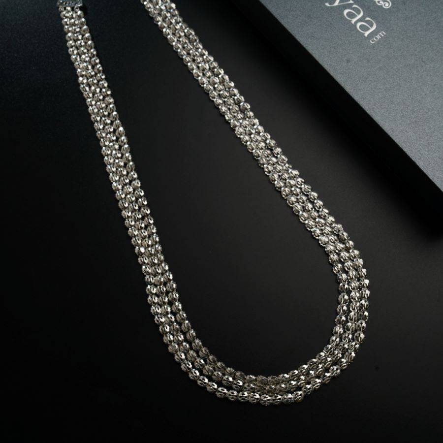 a silver chain is laying on a black surface