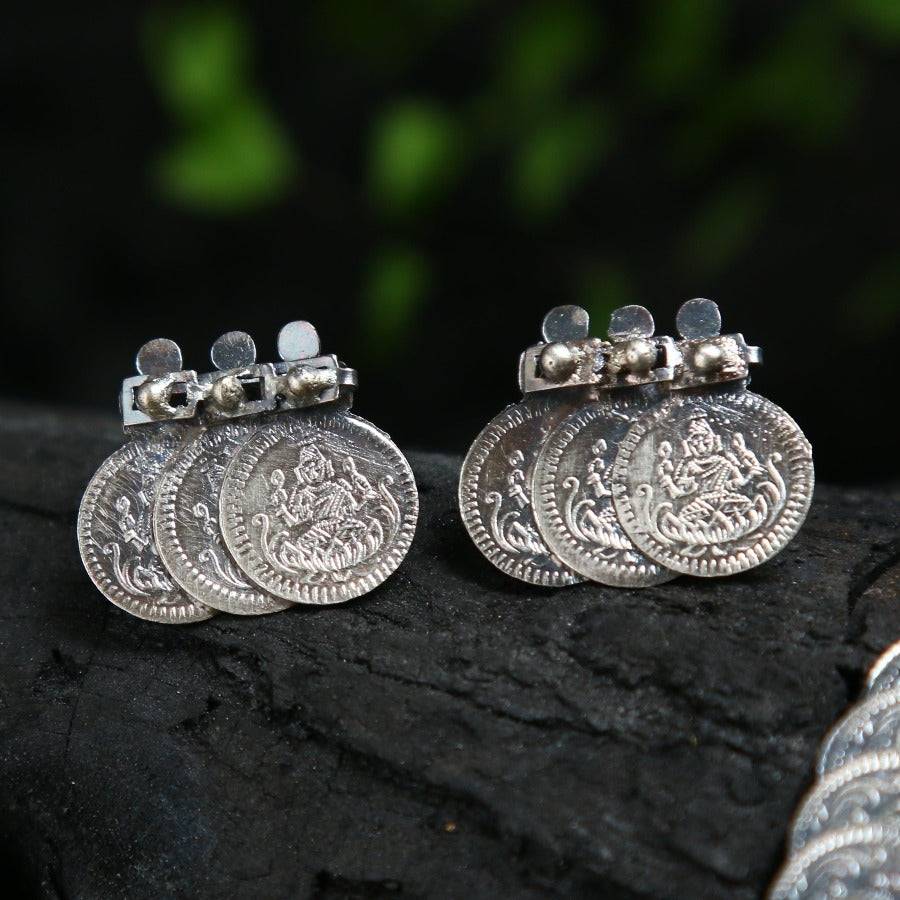 a pair of silver earrings sitting on top of a rock