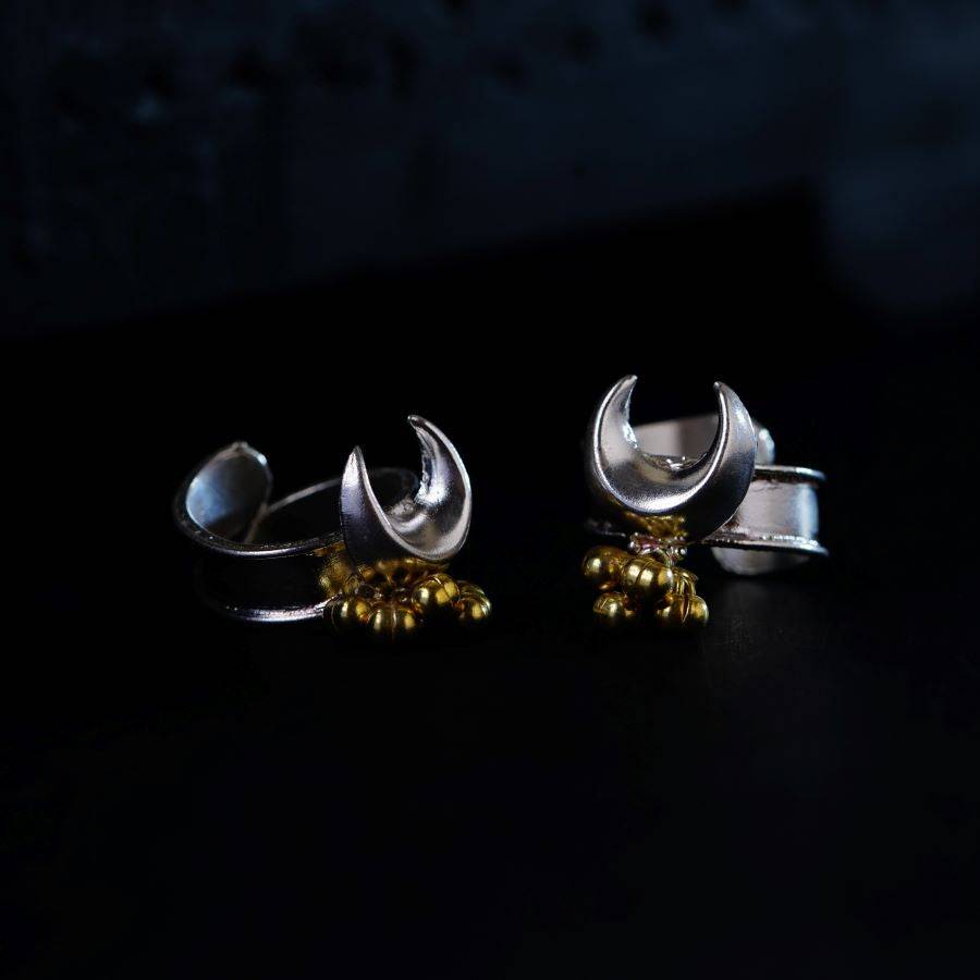 a pair of silver and gold earrings on a black surface